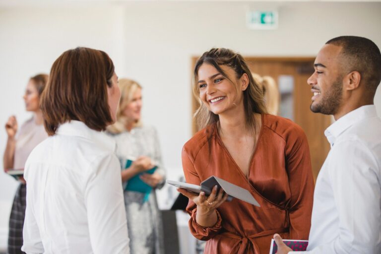 Cheerful young colleagues discussing with digital tablet